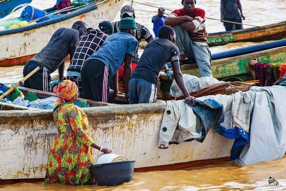 Pêcheurs et commerçantes autour des pirogues sur la plage